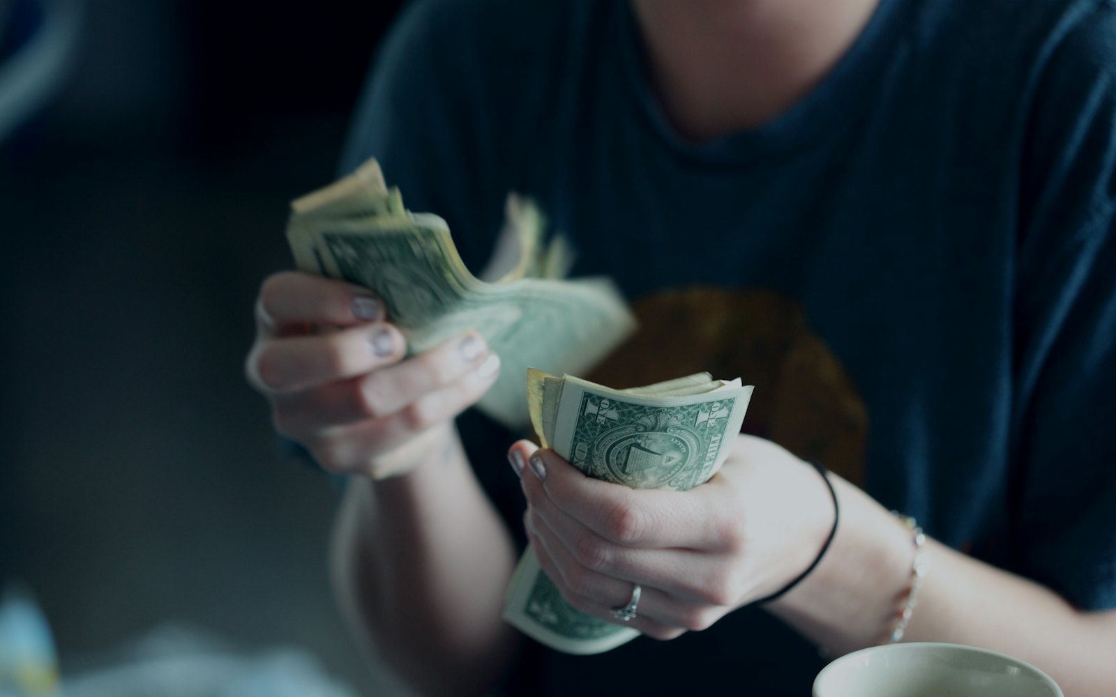 Hands counting dollar bills in low light
